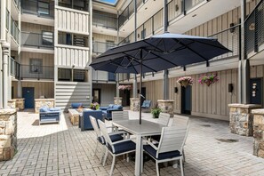 A multi-level outdoor patio with a dining table, chairs, and an umbrella. - Westwind 208b Hotel Room in Lionshead Village (Vail)