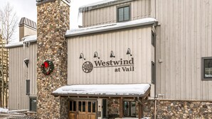 Ein Gebäude mit einem Steinturm, einem Schild mit der Aufschrift 'Westwind at Vail' und einem überdachten Eingang.
