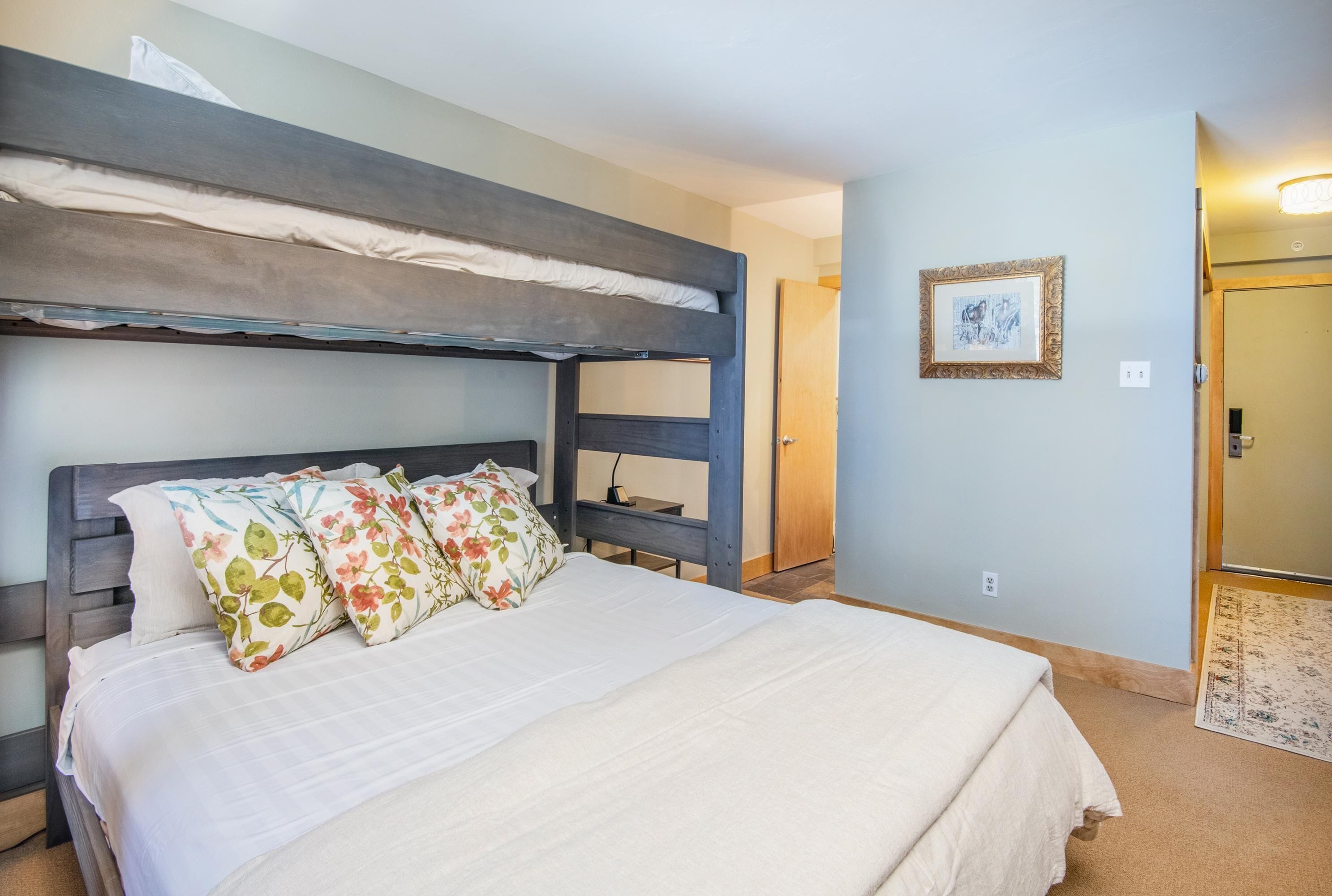A bunk bed with a white mattress, floral pillows, and a wooden headboard.