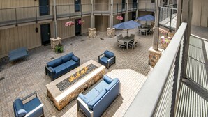 Ein Terrassenbereich im Freien mit Sitzgelegenheiten, einer Feuerstelle und Blick ins Innere des Gebäudes.
