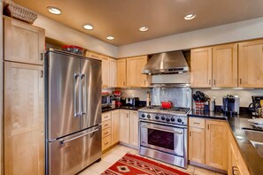 A modern kitchen with stainless steel appliances, wooden cabinets, and a red patterned rug. - Creekside Penthouse, 3BD + Loft in Vail Village (Vail)