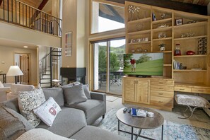 A spacious living room with a grey sofa, a coffee table, and a TV on a wooden cabinet. - Creekside Penthouse, 3BD + Loft in Vail Village (Vail)