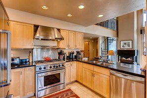 A modern kitchen with stainless steel appliances, wooden cabinets, and a black countertop. - Creekside Penthouse, 3BD + Loft in Vail Village (Vail)