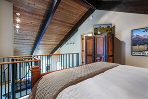 A bedroom with a wooden ceiling, a bed with a quilt, a wooden wardrobe, and a poster on the wall. - Creekside Penthouse, 3BD + Loft in Vail Village (Vail)