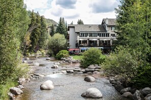 A riverside hotel with a stone pathway, outdoor seating, and a mountain backdrop. - Creekside Penthouse, 3BD + Loft in Vail Village (Vail)