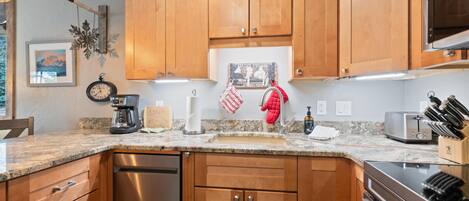 A kitchen with wooden cabinets, a stainless steel dishwasher, a granite countertop, a toaster, and a knife block.