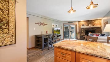 A kitchen with a granite countertop, wooden cabinets, and pendant lighting.