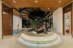 Un interior moderno con una escalera de caracol, una piscina y una escultura central.