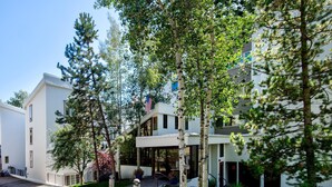 A modern building with a covered entrance, surrounded by trees and a flag. - Treetops 6A, 3BD Ski-in Ski-out Condo (Vail)