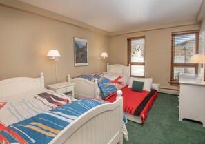 A bedroom with two beds, a nightstand, a desk, and a window with blinds. - Treetops 6A, 3BD Ski-in Ski-out Condo (Vail)