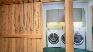 A laundry room with two washing machines, wooden walls, and a green carpet. - Treetops 6A, 3BD Ski-in Ski-out Condo (Vail)