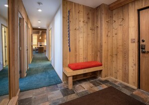 A hallway with wooden walls, a bench with a red cushion, and a door with a handle. - Treetops 6A, 3BD Ski-in Ski-out Condo (Vail)