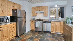 Una cocina moderna con armarios de madera, un refrigerador de acero inoxidable, horno empotrado y lavavajillas.