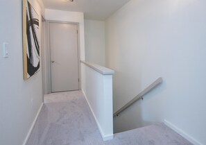A hallway with a carpeted floor, a white door, and a white wall. - Gore Circle Chalet, 4BD 3BA Private East Vail Home (Vail)