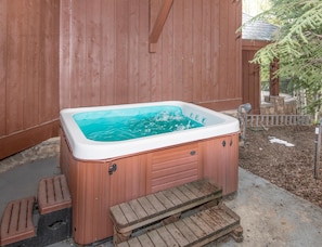 Ein Whirlpool mit Stufen, einer Holzterrasse und einem Holzzaun.