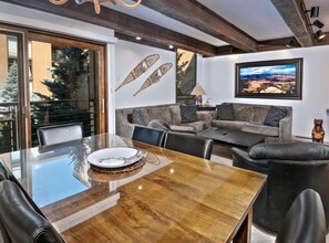 A modern living room with a glass dining table, leather chairs, a grey sofa, and a large framed landscape painting. - Vail International 108, 2 BD Lionshead Village Condo (Vail)