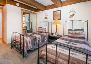 Ein Zimmer mit zwei Betten, einem Nachttisch, einer Lampe und einem Spiegel.