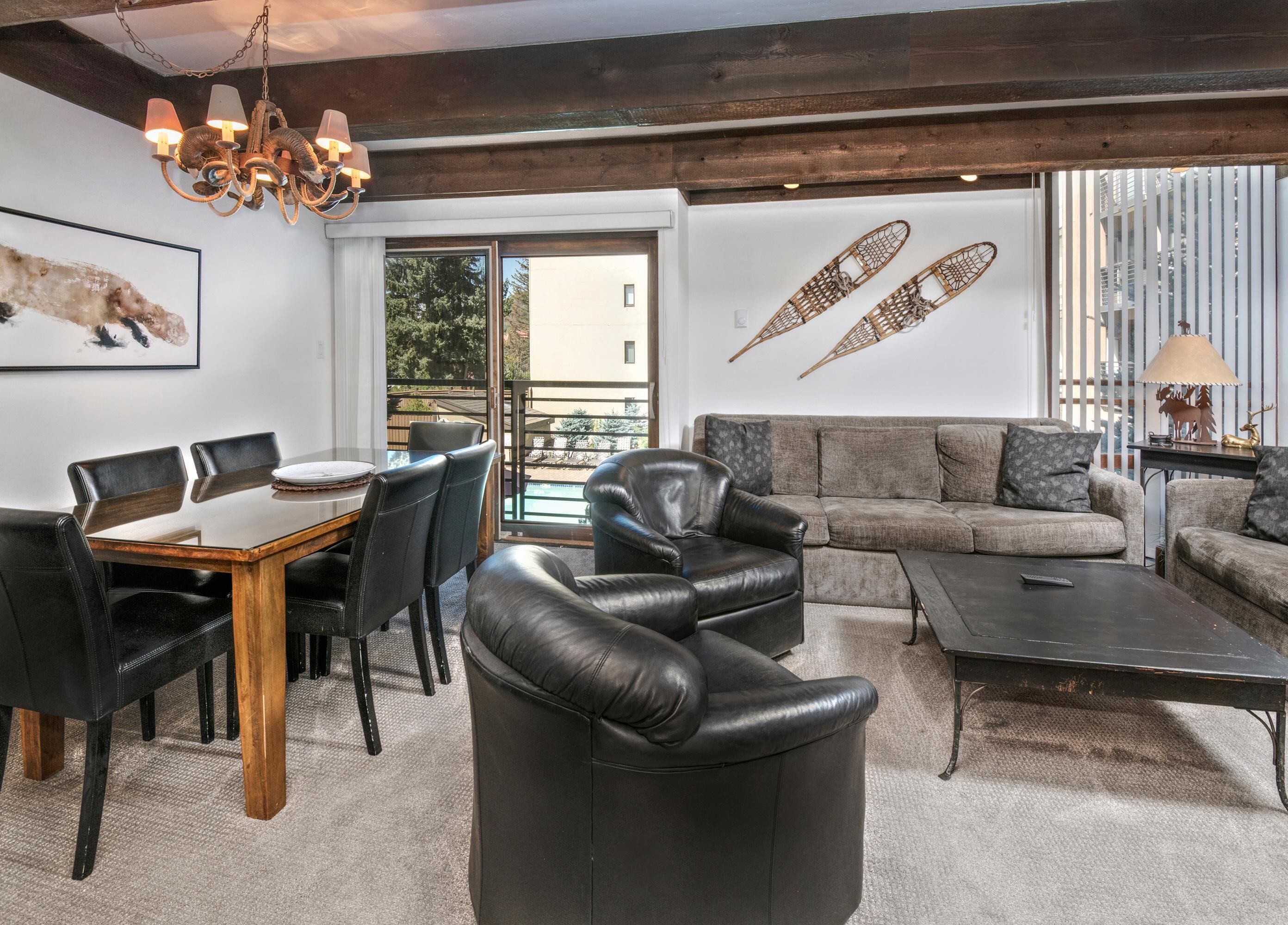 A modern living room with a dining table, leather chairs, a sofa, and a coffee table.