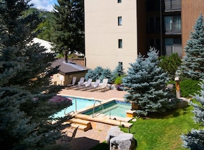 A pool area with lounge chairs, a hot tub, and a building with multiple floors. - Vail International 108, 2 BD Lionshead Village Condo (Vail)
