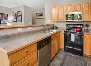A modern kitchen with wooden cabinets, stainless steel appliances, and a granite countertop. - Sun Vail 13e, 2bd, 2BA Condo With Vail Mountain Views (Vail)