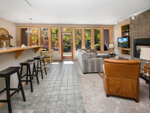 A living room with a sofa, a brown leather chair, a TV, and a fireplace. - Sun Vail 13e, 2bd, 2BA Condo With Vail Mountain Views (Vail)