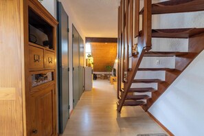 Eine Holztreppe führt zu einer erhöhten Galerie mit Holzboden und Blick auf eine Küchenzeile.