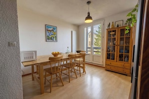 Ein Essbereich mit einem Holztisch und Stühlen, einem Schrank mit Glastüren und einem Bild an der Wand.