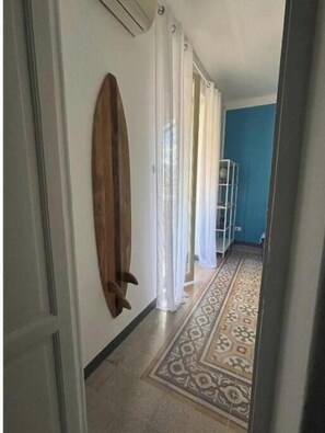 Ein Flur mit einem gemusterten Boden, einem Surfbrett an der Wand und einer blauen Wand.