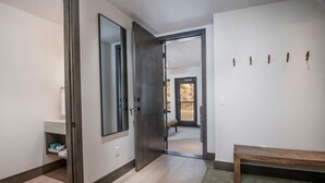 A hallway with a wooden bench, a mirror, and a door leading to another room. - Altus 305, 3BD Vail Village Condo With Views (Vail)