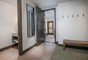 A hallway with a wooden bench, a mirror, and a door leading to another room. - Altus 305, 3BD Vail Village Condo With Views (Vail)