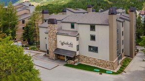 A multi-story hotel with a stone facade, named 'Westwind at Vail,' surrounded by lush greenery and mountains. - Westwind 209 1bd, 1BA Platinum Condo in Lionshead Village (Vail)