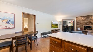 A modern kitchen with a large island, wooden dining table, and chairs. There is a bench and a fireplace. - Westwind 209 1bd, 1BA Platinum Condo in Lionshead Village (Vail)