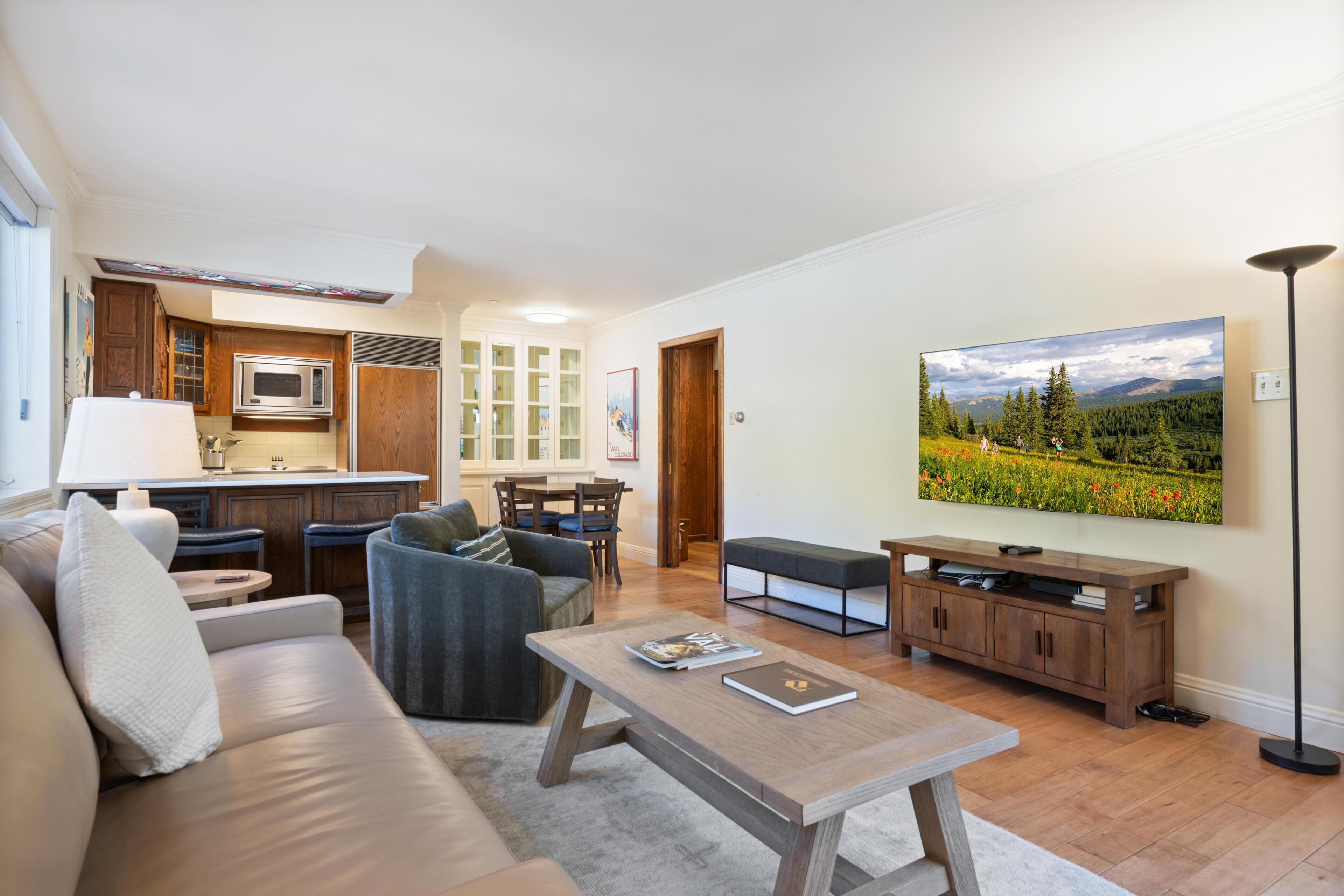 A living room with a sofa, coffee table, and a TV mounted on the wall.