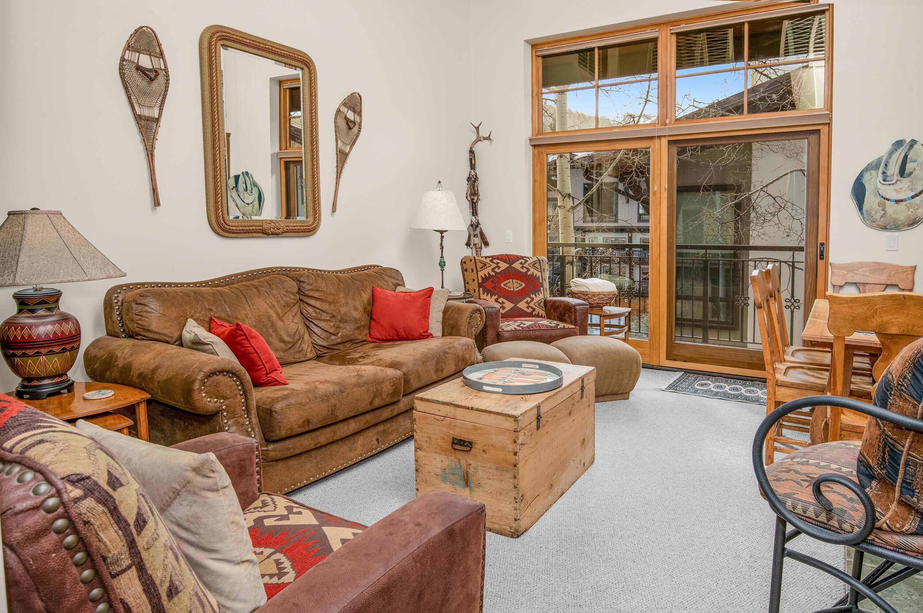 A living room with a brown sofa, a wooden chest, and a patterned armchair.