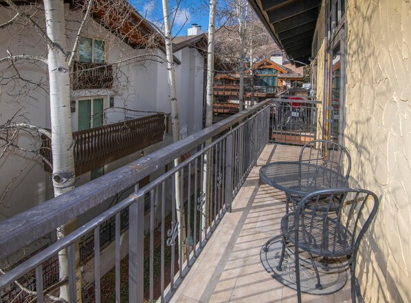 Ein Balkon mit Metallgeländer, einem Tisch und Stühlen.