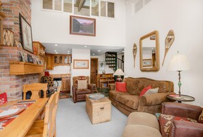 Ein gemütliches Wohnzimmer mit Kamin, Holzmöbeln, einer Treppe und einem großen Spiegel.