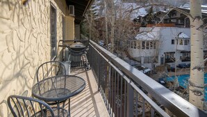 Een balkon met twee metalen stoelen, een tafeltje en een hekwerk.
