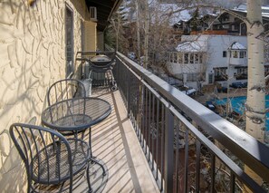 Ein Balkon mit zwei Metallstühlen, einem kleinen Tisch und einem Geländer.