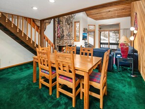 Ein Essbereich mit Holztisch und Stühlen, einer Treppe, einem Steinkamin und einem blauen Sofa.