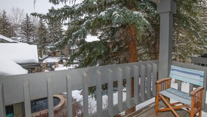 A wooden deck with a bench, snow-covered trees, and a house in the background. - Ridgepoint 187, 3BD Townhome in Beaver Creek (Avon)