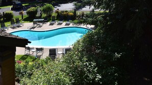 A swimming pool with lounge chairs and a covered area, surrounded by greenery and a residential building in the background. - Ridgepoint 187, 3BD Townhome in Beaver Creek (Avon)