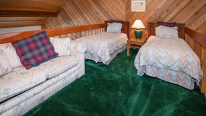 A room with a sloped ceiling, two single beds with matching headboards, a sofa with a plaid pillow, a small table with a lamp, and a framed picture on the wall. - Ridgepoint 187, 3BD Townhome in Beaver Creek (Avon)