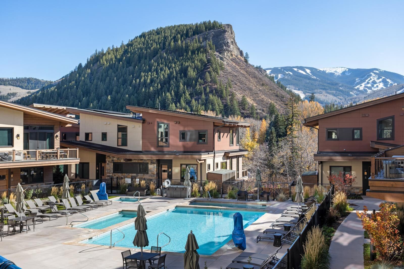 Un resort con piscina, mobiliario exterior y vistas a la montaña.