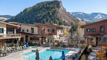 Un resort con piscina, mobiliario exterior y vistas a la montaña.