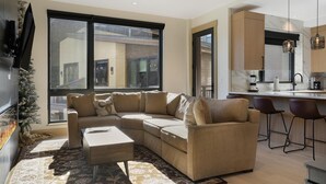 Ein modernes Wohnzimmer mit einer Eckcouch, einem Couchtisch und einem großen Fenster mit Blick auf die Stadt.