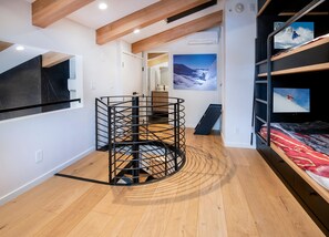 Ein Zimmer mit Etagenbett, einer runden Metallkonstruktion, einem an der Wand befestigten Fernseher und einem großen Fenster mit Blick auf die Berge.