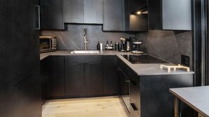 A modern kitchen with dark cabinetry, a built-in oven, and a wooden countertop. - Wall Street 302, 1BD + Loft Condo in Vail Village (Vail)