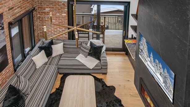 A modern living room with a sectional sofa, a coffee table, a black rug, and a fireplace. - Wall Street 302, 1BD + Loft Condo in Vail Village (Vail)