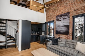Ein modernes Interieur mit Treppe, Küche, Essbereich und einer Couch mit Blick auf einen verschneiten Berg.