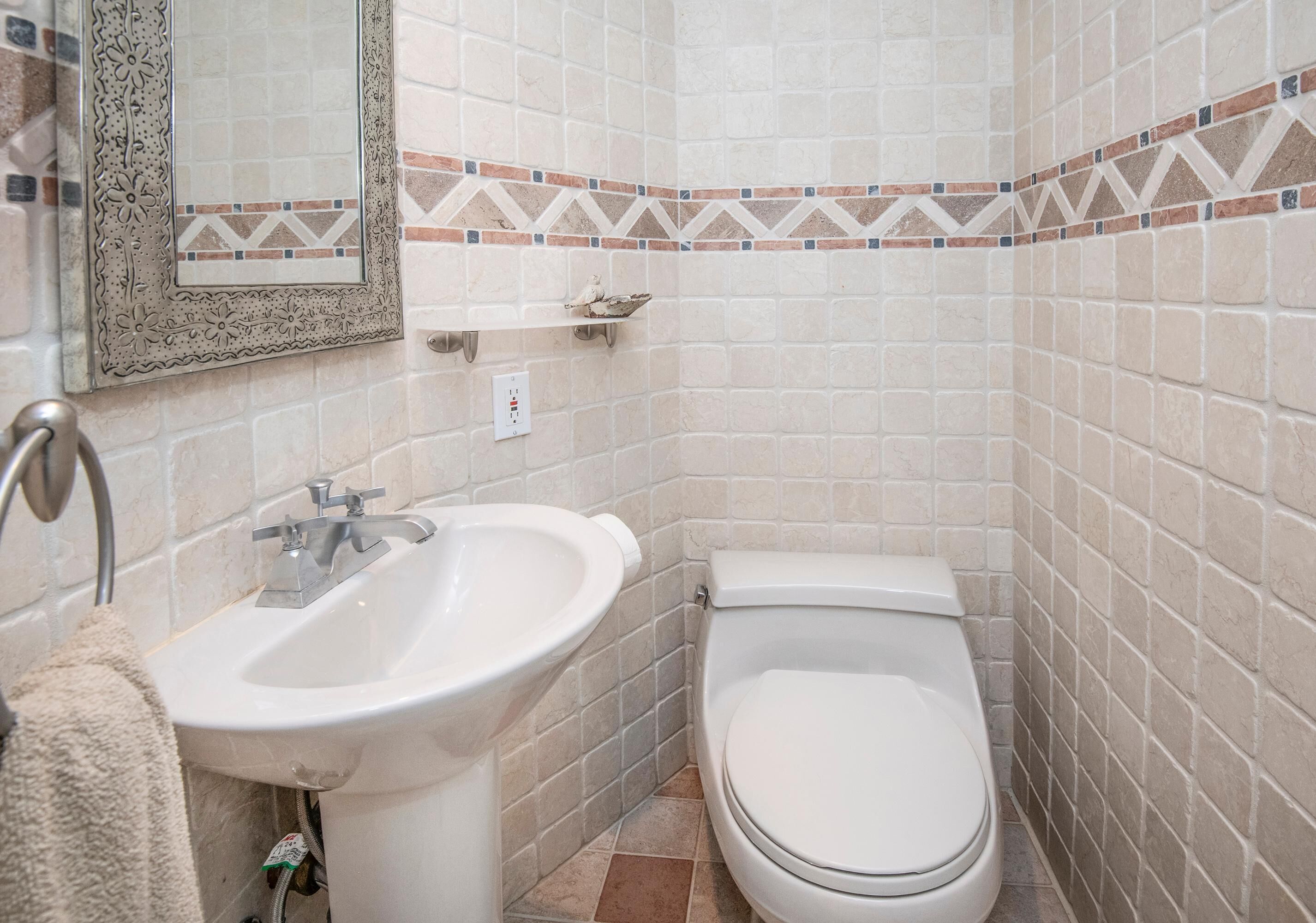 A bathroom with a sink, toilet, and a mirror with a decorative frame.